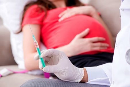 pregnant woman with doctor holding vaccine needle