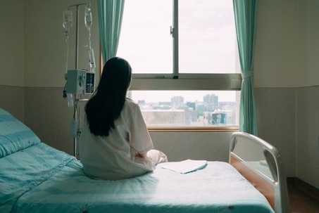 female patient sitting on her hospital bed looking out the window